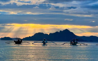 Sun setting over the islands and boats of Palawan Philippines